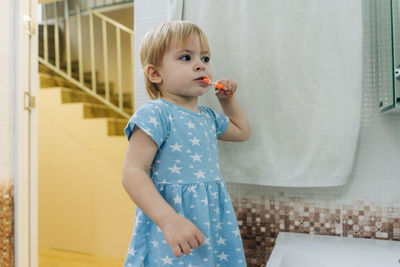 Little toddler girl brushes her teeth in the bathroom.