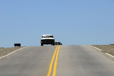 Car on road against clear blue sky