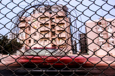Close-up of basketball hoop seen through chainlink fence