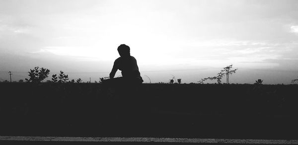 Silhouette man standing on shore against sky during sunset