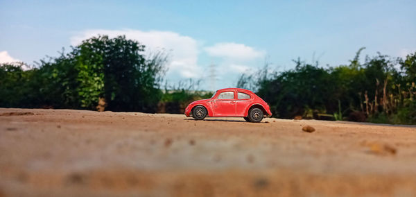 Toy car on road by trees on field against sky