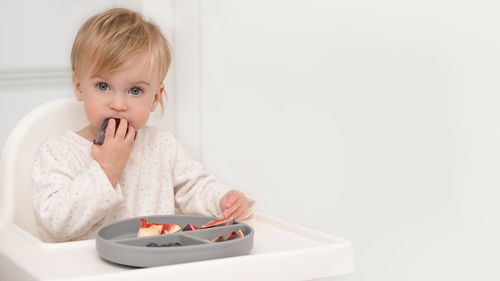 Portrait of cute girl eating fig at home