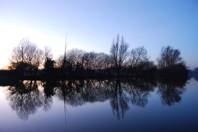 Reflection of trees in lake against clear sky