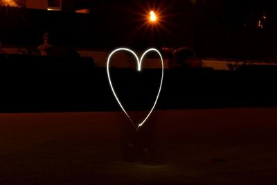 Reflection of silhouette man on heart shape at night