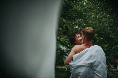 Rear view of couple standing against trees