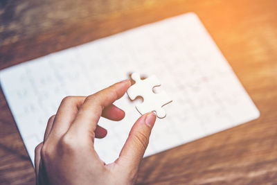 Midsection of person holding paper with text on table