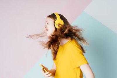 Beautiful woman standing against yellow wall