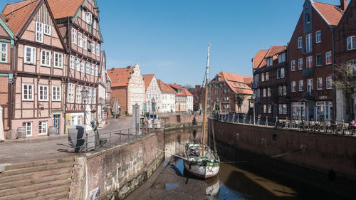 Boats in canal amidst buildings in city against sky