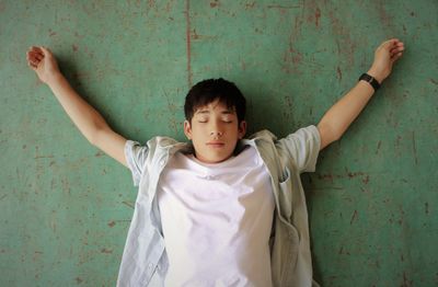 Boy with arms outstretched standing against wall