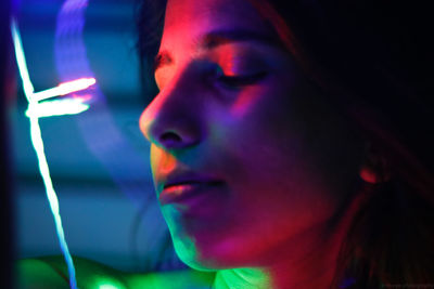 Close-up of woman by illuminated string light