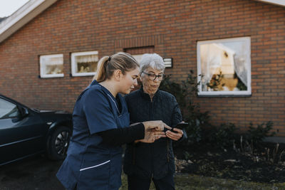 Home caretaker helping senior woman use phone