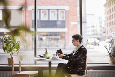 Mature woman using cell phone in cafe