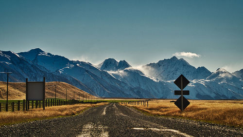 Road leading towards snowcapped mountains against sky