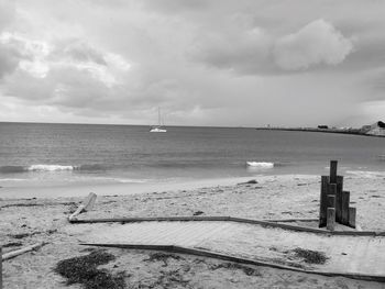 Boats in calm sea against cloudy sky