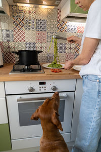 Midsection of woman with dog preparing food at home