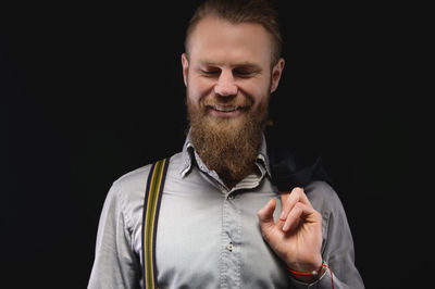 Portrait of a smiling young man against black background