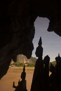Silhouette buddha statues at pak ou caves by river during sunset