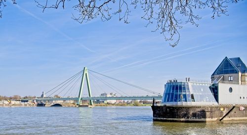 Bridge over river by buildings against sky