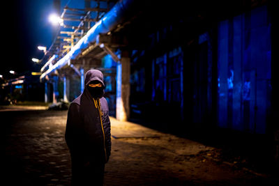 Rear view of man standing in illuminated building at night