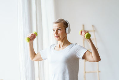 Portrait of senior woman exercising fitness with dumbbells at home. mature female build up biceps