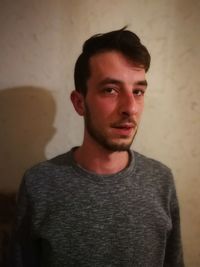 Portrait of young man standing against wall