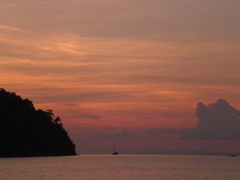 Silhouette boats in calm sea at sunset