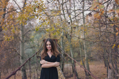 Young woman standing by trees in park