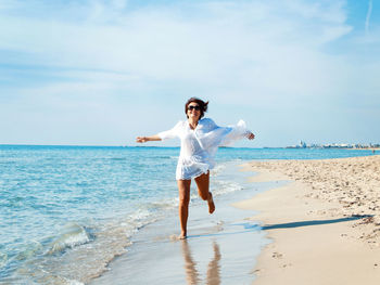 Full length of woman standing at beach against sky