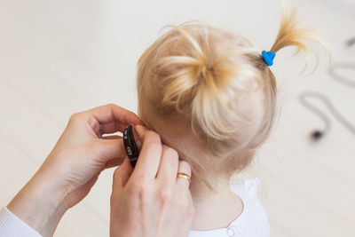 Close-up of mother adjusting hearing aid of daughter