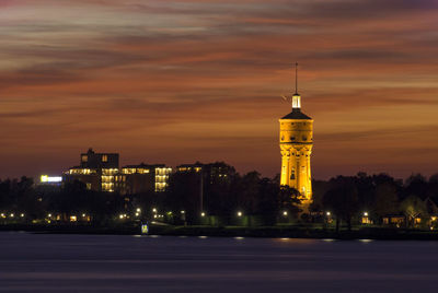 Illuminated buildings against sky at dusk