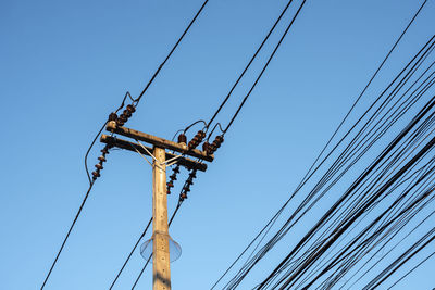 Low angle view of electricity pylon against clear sky