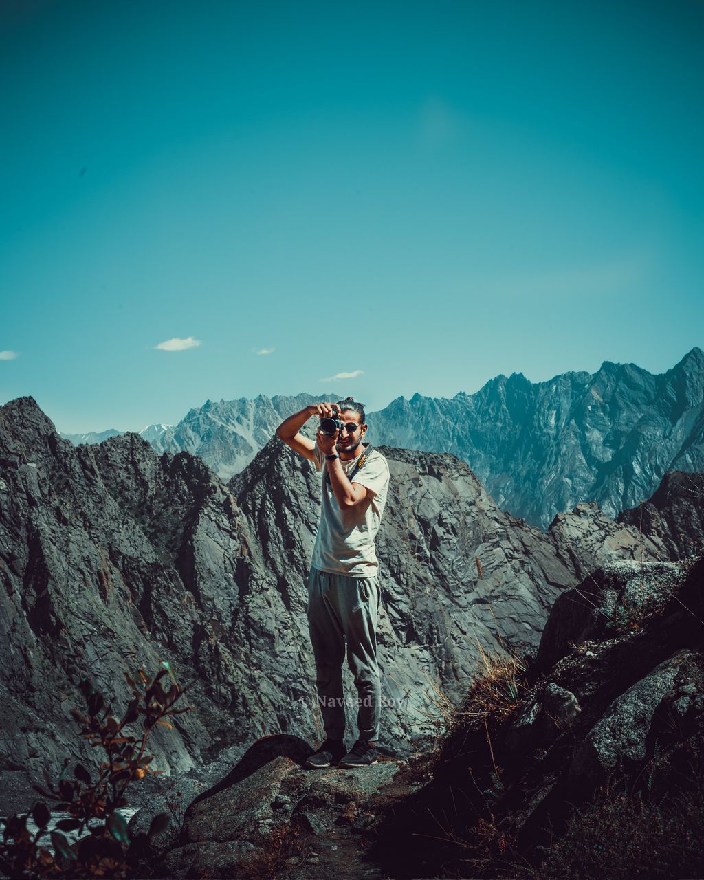 mountain, one person, real people, leisure activity, sky, lifestyles, beauty in nature, young adult, standing, nature, rock - object, rock, activity, clear sky, scenics - nature, photography themes, full length, photographing, mountain range, outdoors