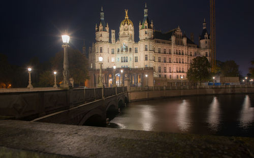 Illuminated bridge over river in city at night