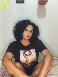 Portrait of young woman against wall at home