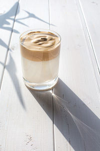 Traditional korean drink, dalgona coffee in a transparent glass on a white board background.