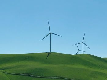 Wind turbines on field against clear sky