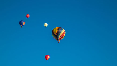 Low angle view of hot air balloons in clear blue sky