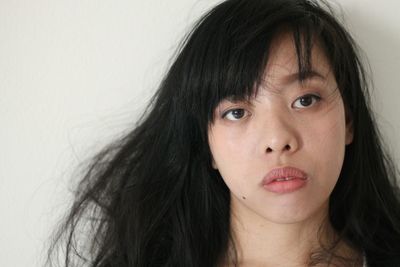 Close-up portrait of sad woman against wall