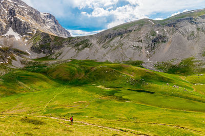 Woman looking at view of mountains against cloudy sky