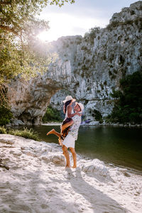 Full length of woman standing on rock against water