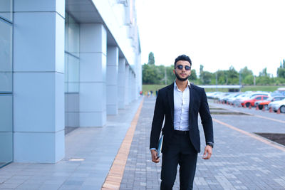 Young businessman standing against building