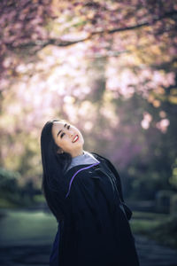 Side view portrait of happy woman wearing graduation gown at park
