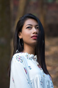 Beautiful young woman standing against tree