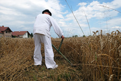 Rear view of man standing on field against sky