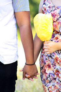 Midsection of young couple holding hands on field