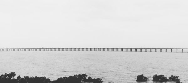 Bridge over sea against clear sky