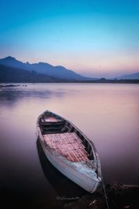 Boat moored at shore against sky during sunset