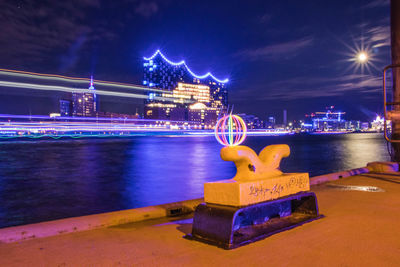 Illuminated light trails on bridge over river at night