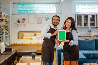 Portrait of smiling female friends using digital tablet while standing in store