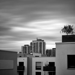 Buildings in city against cloudy sky